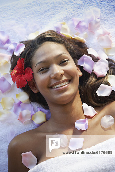 Hispanic woman with flower petals on spa table