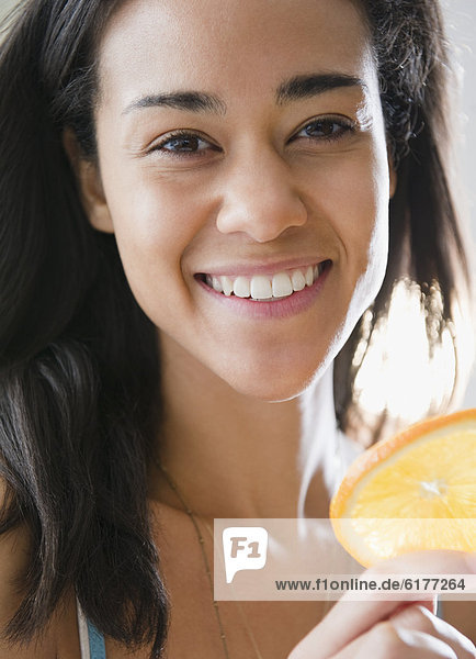 Mixed race woman holding orange slice