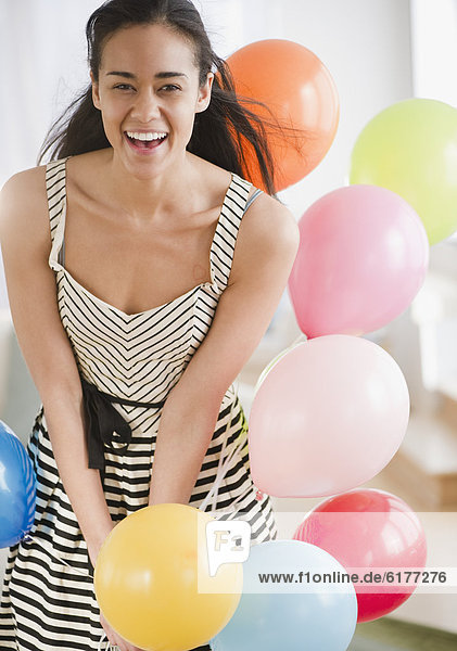 Laughing mixed race woman with balloons