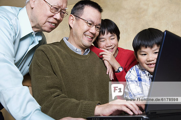 Multi-generational Asian family looking at laptop