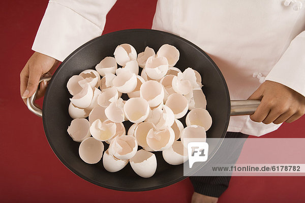 Indian female chef holding pan of egg shells