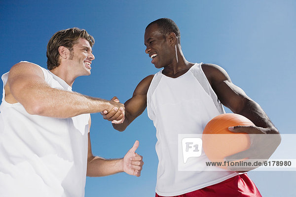 Multi-ethnic men with volleyball shaking hands