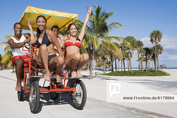 Multi-ethnic couples riding on pedal cart