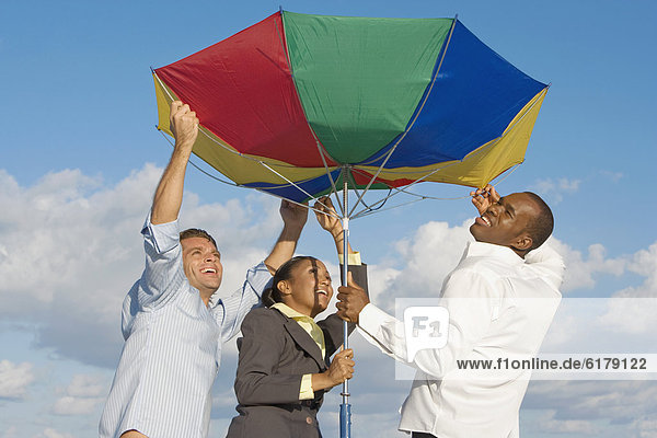 Multi-ethnic businesspeople opening beach umbrella