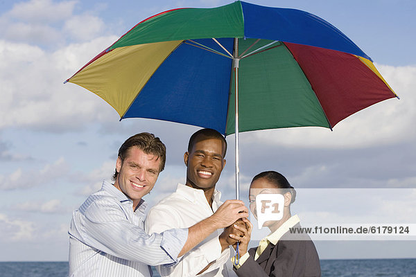 Multi-ethnic businesspeople under beach umbrella