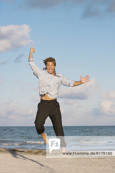 Hispanic man jumping on beach
