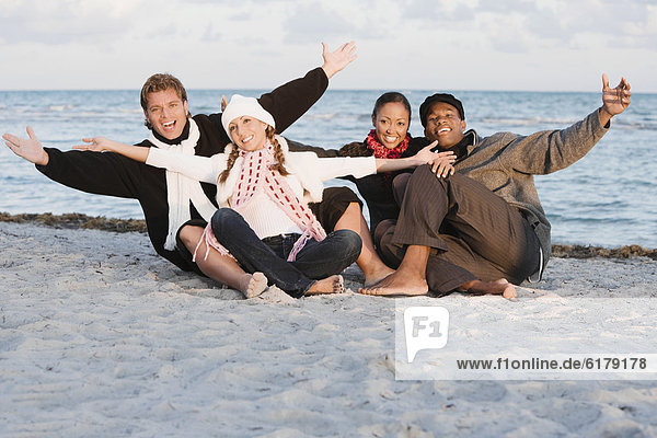 Multi-ethnic couples sitting on beach