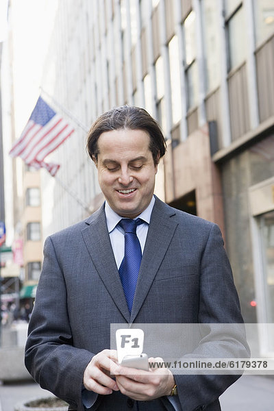 Hispanic businessman text messaging in city