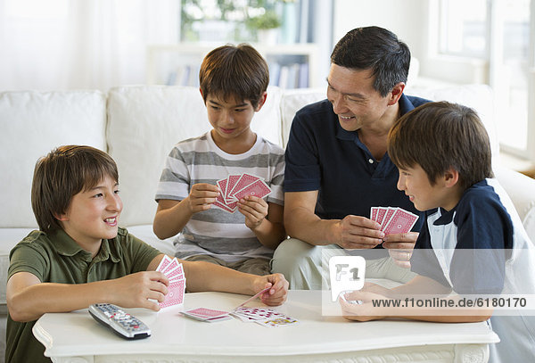 Father and sons playing cards in living room