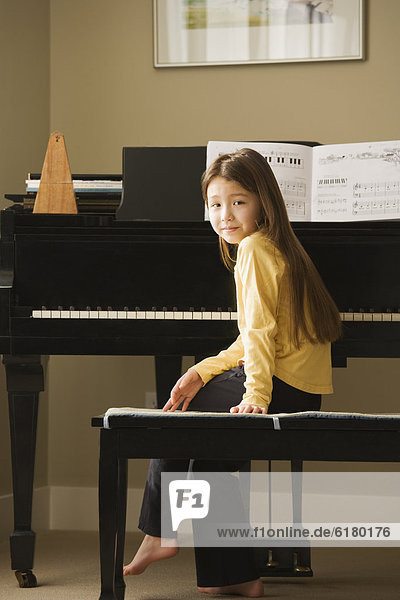 Asian girl sitting at piano
