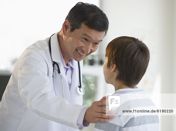 Lächelnder Arzt legt seine Hand auf die Schulter eines Jungen