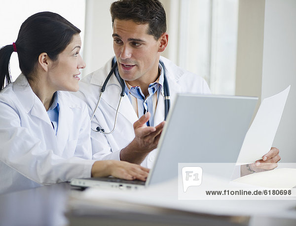 Mixed race doctors working together on laptop