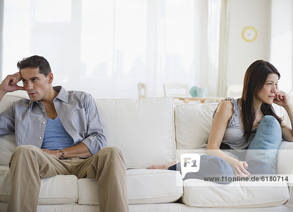 Angry mixed race couple having argument on sofa