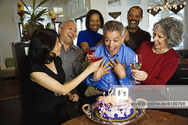 Hispanic man celebrating birthday with multi-ethnic friends