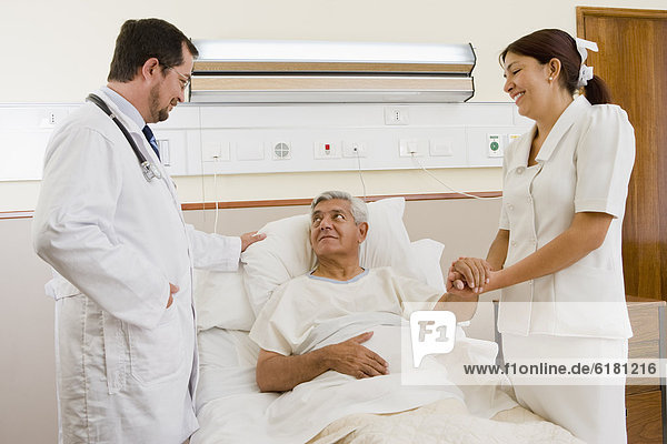 Doctor and nurse talking with patient in hospital room