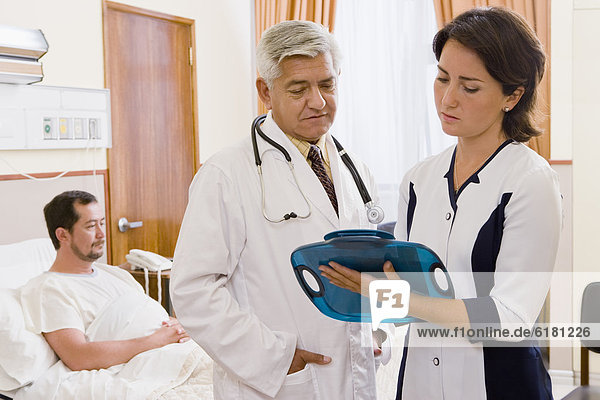Doctor and nurse discussing patient in hospital room