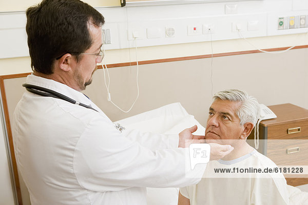 Doctor examining patient's throat in hospital room