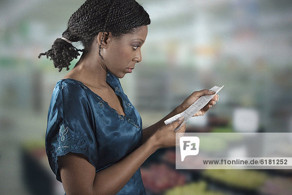 Black woman looking at grocery shopping list