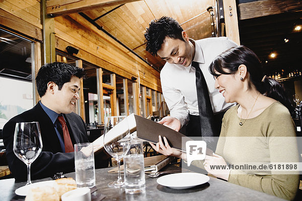 Asian couple reading menu at restaurant