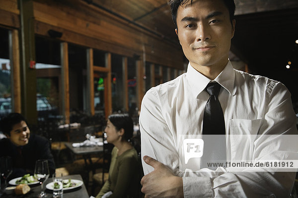 Asian waiter with arms crossed