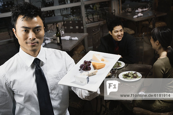 Asian waiter carrying plate of food
