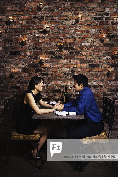Asian couple holding hands at restaurant