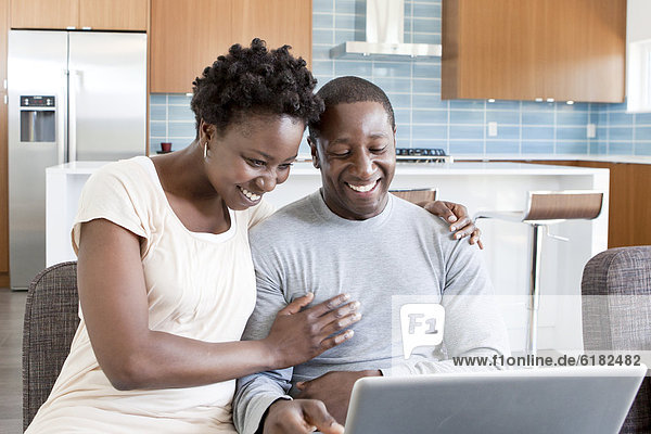Black couple hugging and using laptop