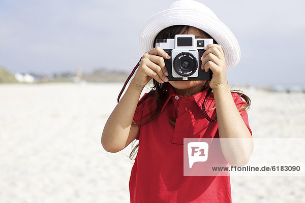 Hispanic girl using old-fashioned camera on beach
