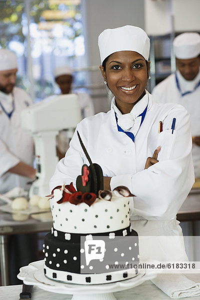 Mixed Race female pastry chef next to cake