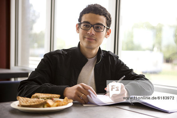 Hispanic student studying in diner and having lunch