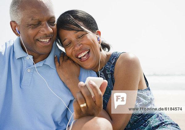 Black couple on beach listening to music together