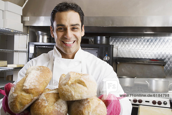 Hispanic male baker holding fresh bread