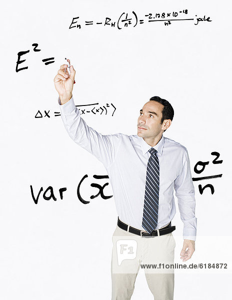 Hispanic businessman writing formula on clear board