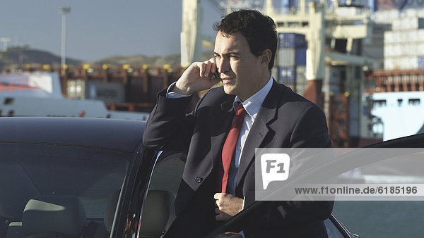 Hispanic businessman talking on cell phone on dock