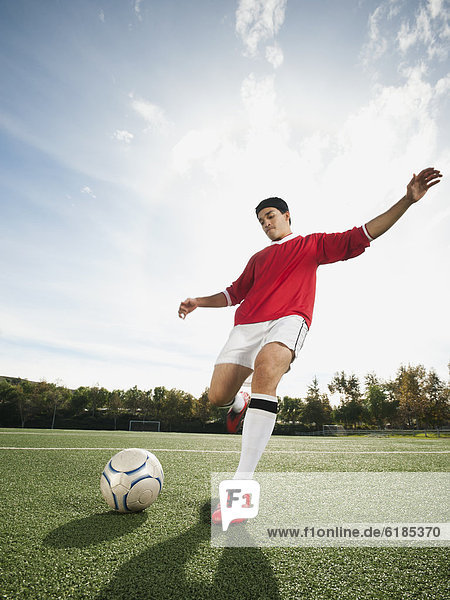 Mixed race soccer player kicking soccer ball