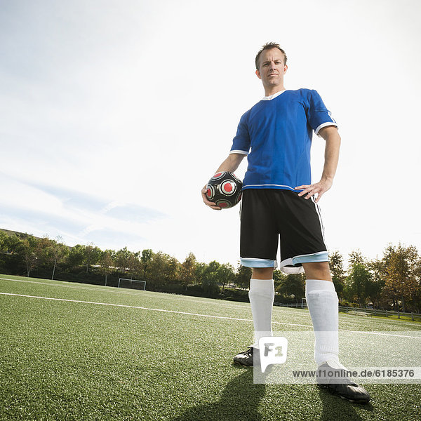Caucasian soccer player holding ball on soccer field