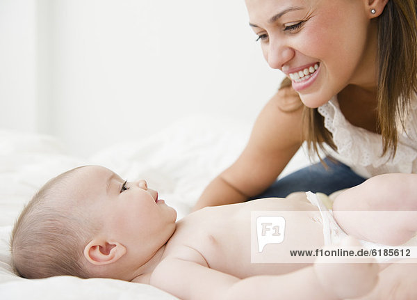 Mother smiling with baby on bed