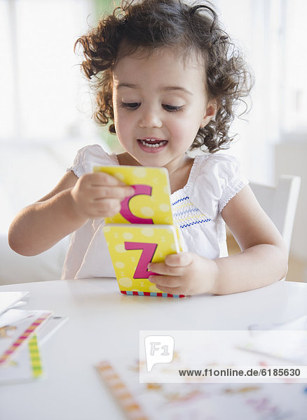 Mixed race girl playing with alphabet cards