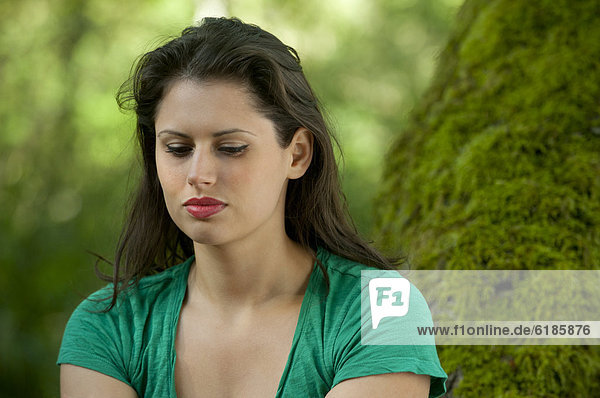 Serious Caucasian woman sitting in forest