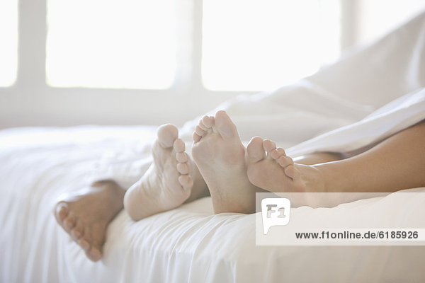 Close up of couple's feet in bed