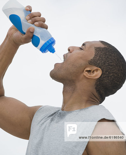 African man drinking from water bottle
