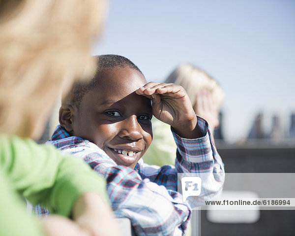Boy on rooftop with friends shielding eyes