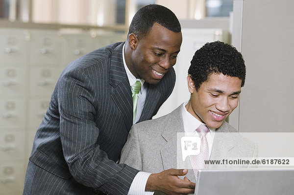 Multi-ethnic businessmen working on laptop in office