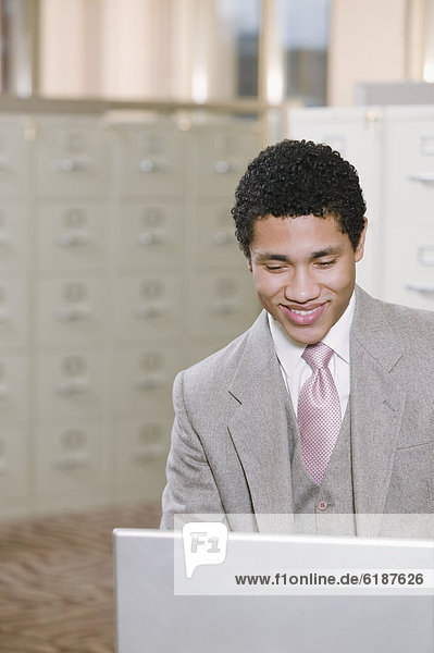 Mixed race businessman working on laptop in office