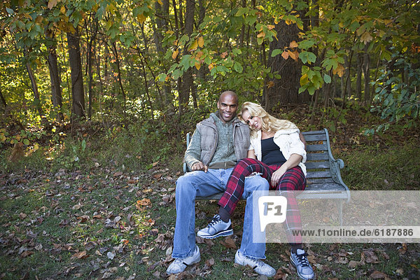 Couple sitting on park bench in autumn