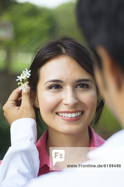 Hispanic husband putting flower behind wife's ear