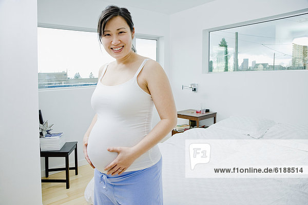 Pregnant Asian woman holding stomach