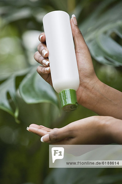 Mixed race woman pouring lotion into hand