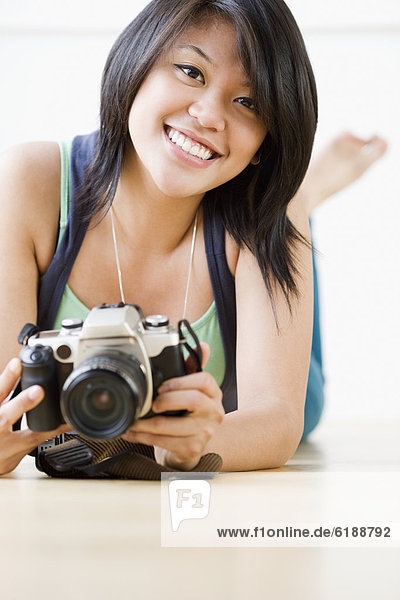 Asian woman laying on floor with camera