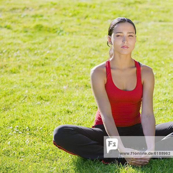 Hispanic woman stretching in grass